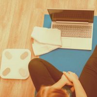 woman-sportswear-make-remote-yoga-exercise-yoga-class-seated-during-stay-home-young-woman-fitness-workout-stretching-exercises-using-laptop-via-videocall-towel-scales-laptop-top-view-scaled-orangepeel